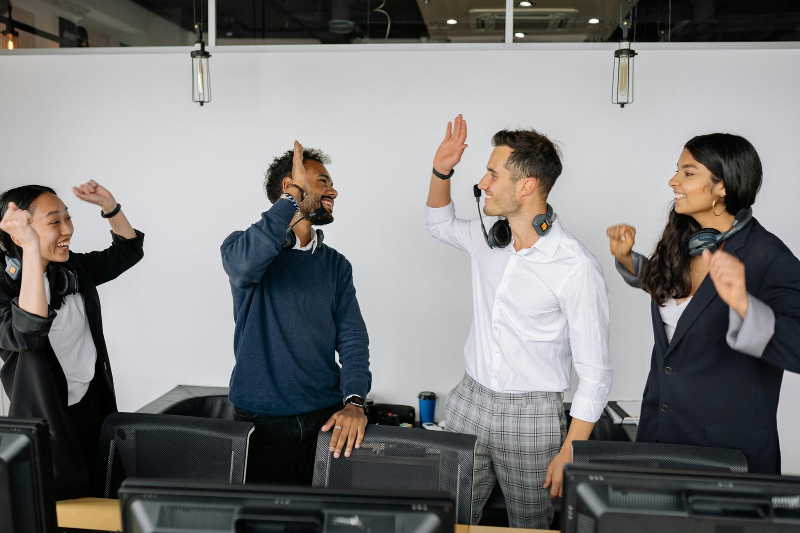 A diverse group of coworkers high-fiving in a modern office, showcasing teamwork and success.